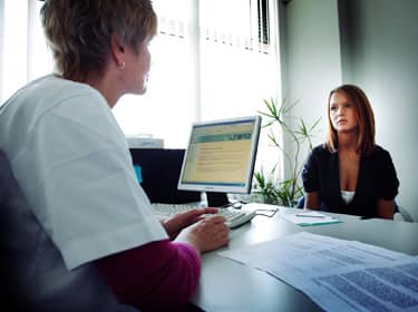 De foto toont een tienermeisje in gesprek met haar huisarts