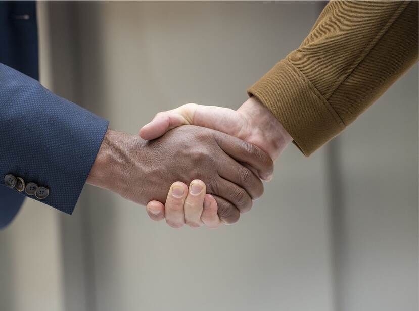De foto toont 2 handen die elkaar schudden.
